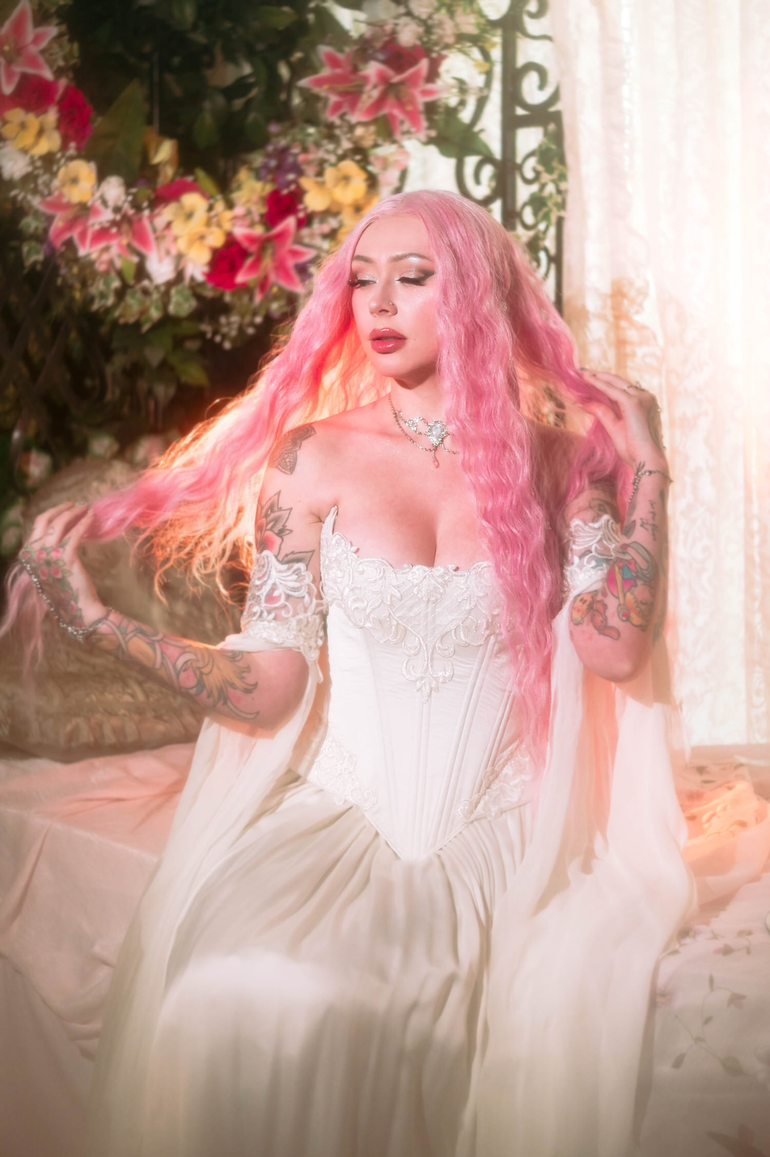 Firefly path bridal gown detail shot with bride lifting her pink hair, surrounded by cascading florals in a fantasy wedding photography set.