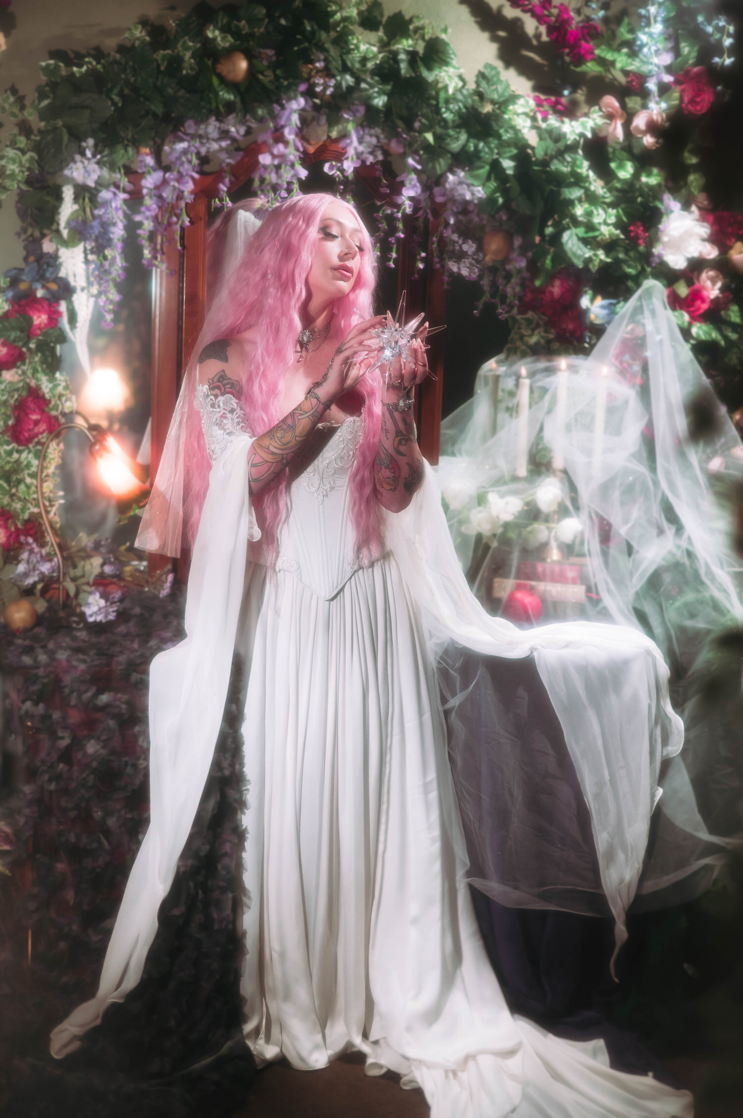Fantasy wedding photography portrait of bride holding a crystal star prop, surrounded by lush florals, candles, and draped veil at Royal Lune Studio.