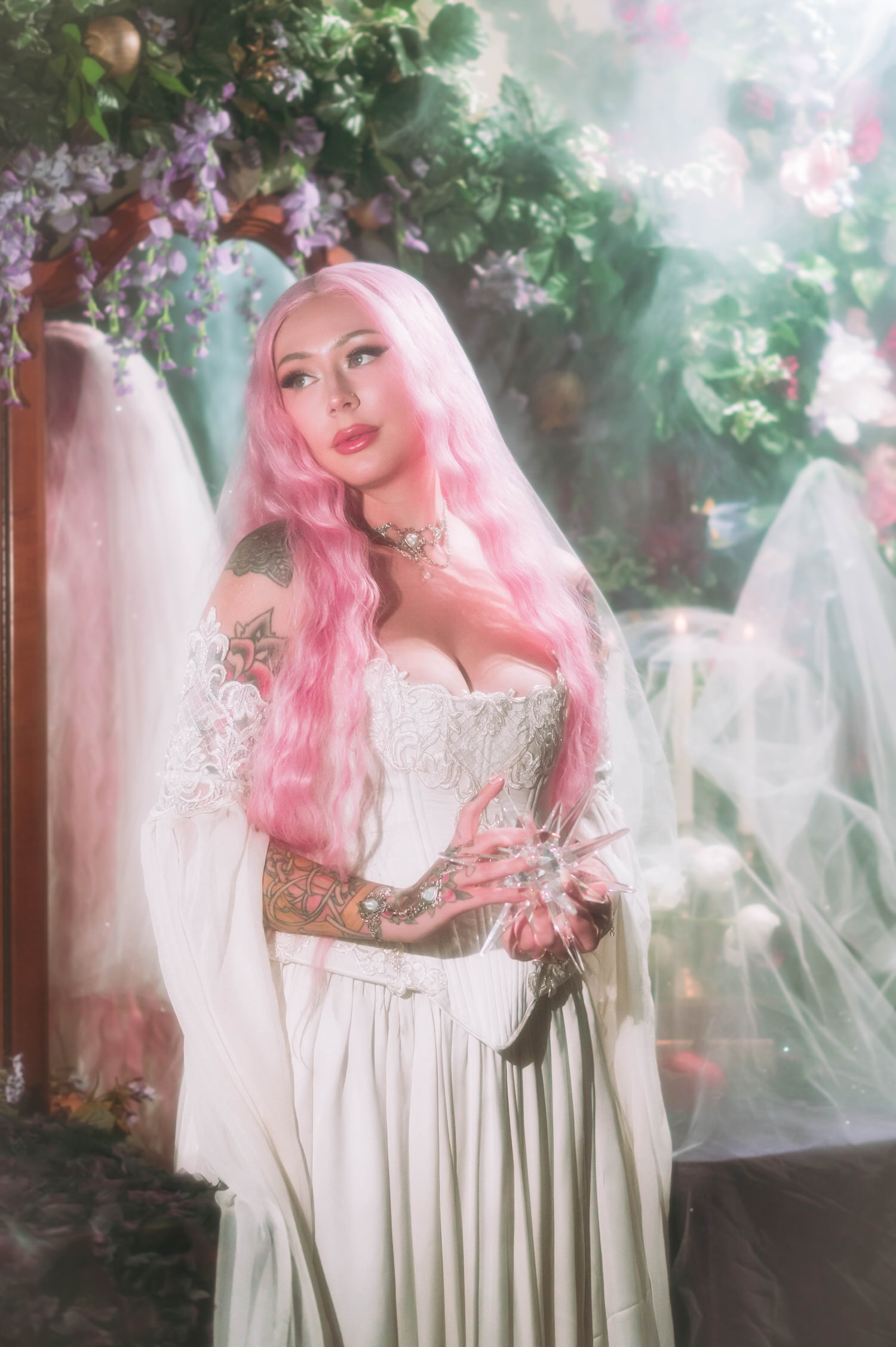 Close-up fantasy bridal photos of bride in embroidered corset and veil, holding a faceted crystal star against a dreamy greenery backdrop.