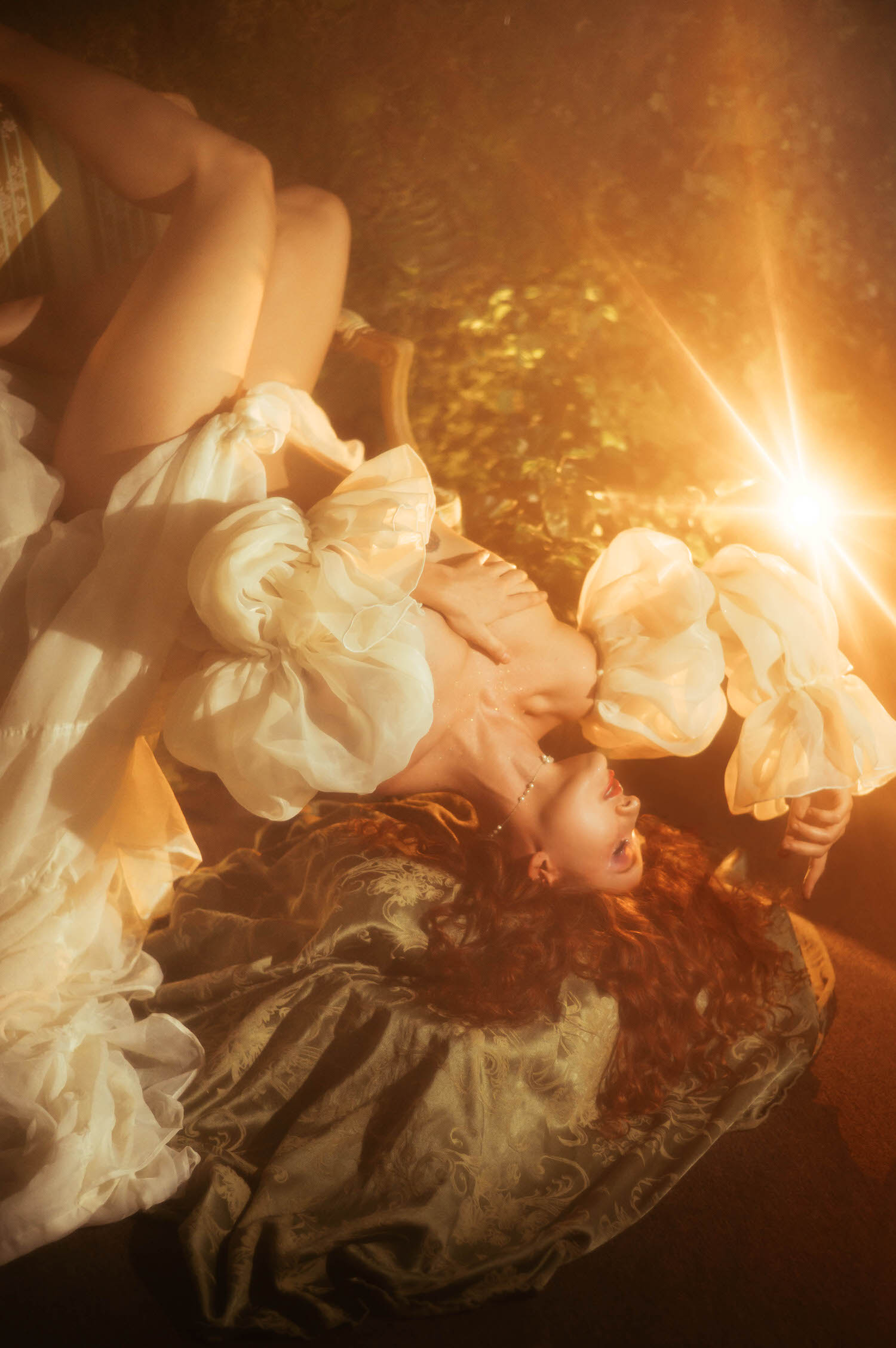 A fine art nude portrait on an antique chaise lounge with sheer ivory fabric draped artfully, captured in warm golden light reflecting the dreamy photography studio aesthetic of a Midsummer Night's Dream photoshoot. This artistic image was captured near Dallas. Royal Lune Photo.