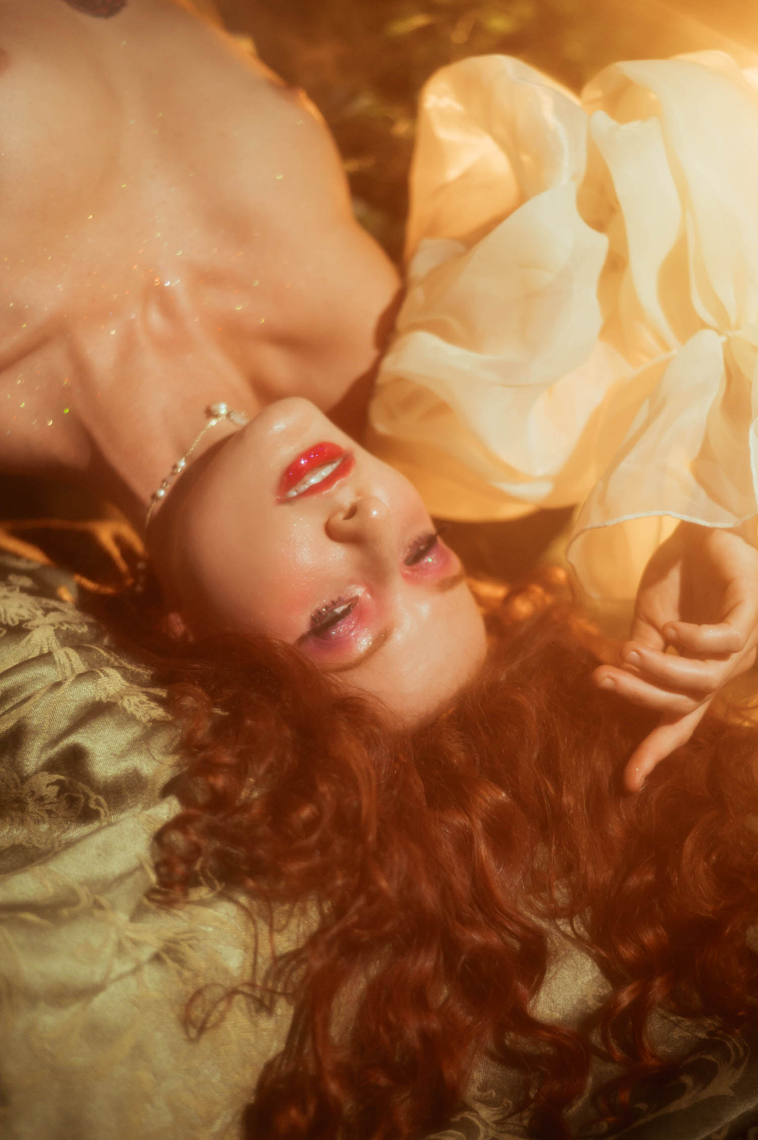 A close up fine art beauty portrait featuring glossy red lips and curly red hair, captured in warm golden light for a dreamy photography studio session inspired by A Midsummer Night's Dream. This artistic image was created near Dallas. Royal Lune Photo.