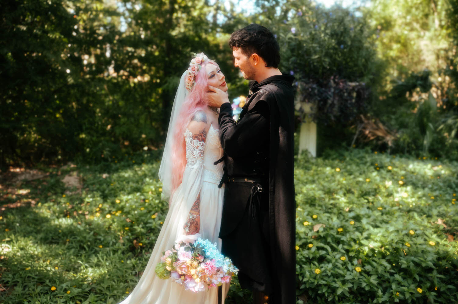The groom gently cradles the bride's face as they gaze at each other surrounded by lush greenery and wildflowers. Tender moments like this are exactly what couples look for in a fantasy wedding photographer. Royal Lune Photo.