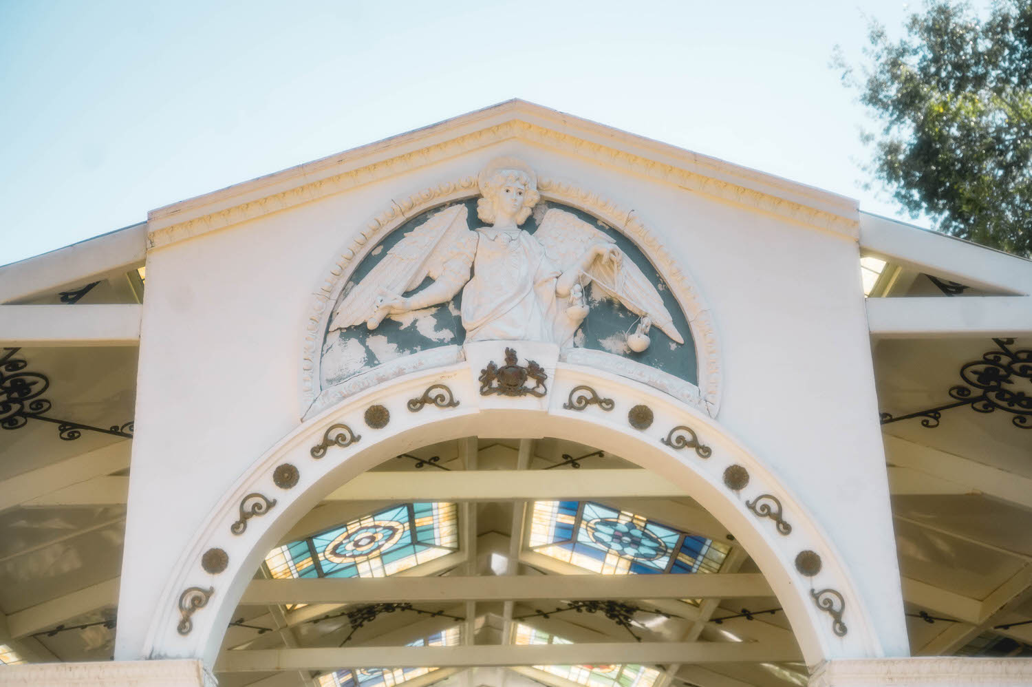 A carved angel relief sits above the arched entrance of the Basilica Wedding Chapel, framed by colorful stained glass and ornate ironwork. Architectural details like this make the venue a stunning choice for a Renaissance festival wedding. Royal Lune Photo.