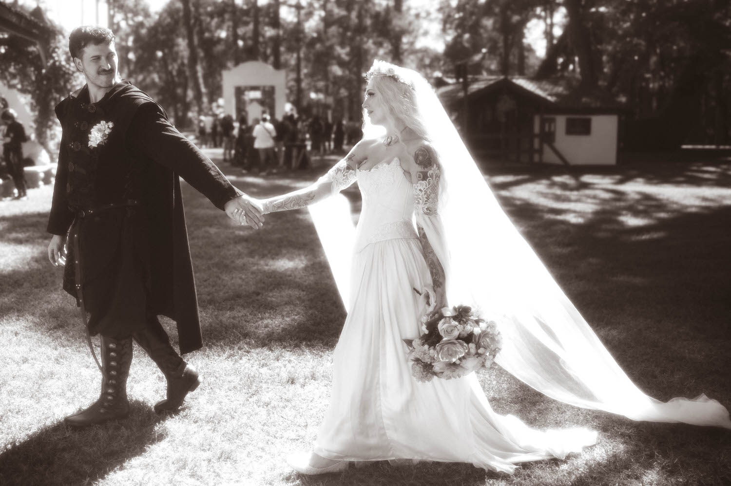 In this black and white image, the groom leads the bride by the hand across the grass, her veil and gown trailing behind her in the sunlight. Joyful in between moments like this are part of what makes a Texas Renaissance Festival wedding so special to document. Royal Lune Photo.