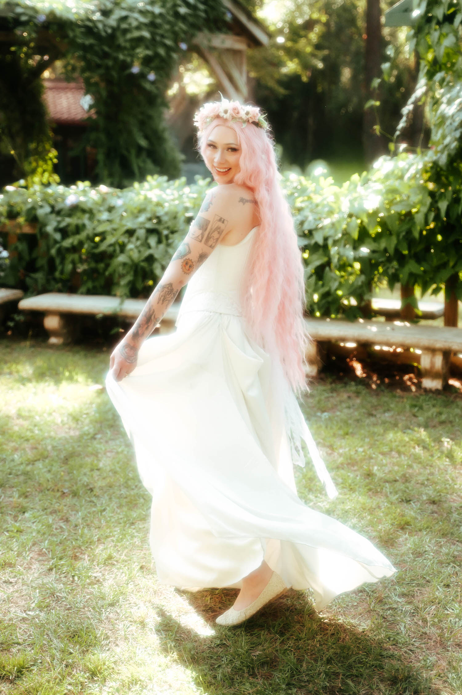 The bride glances over her shoulder while swishing her gown, showing off the delicate tattoo work along her arm at this Texas Renaissance Festival wedding. Royal Lune Photo.