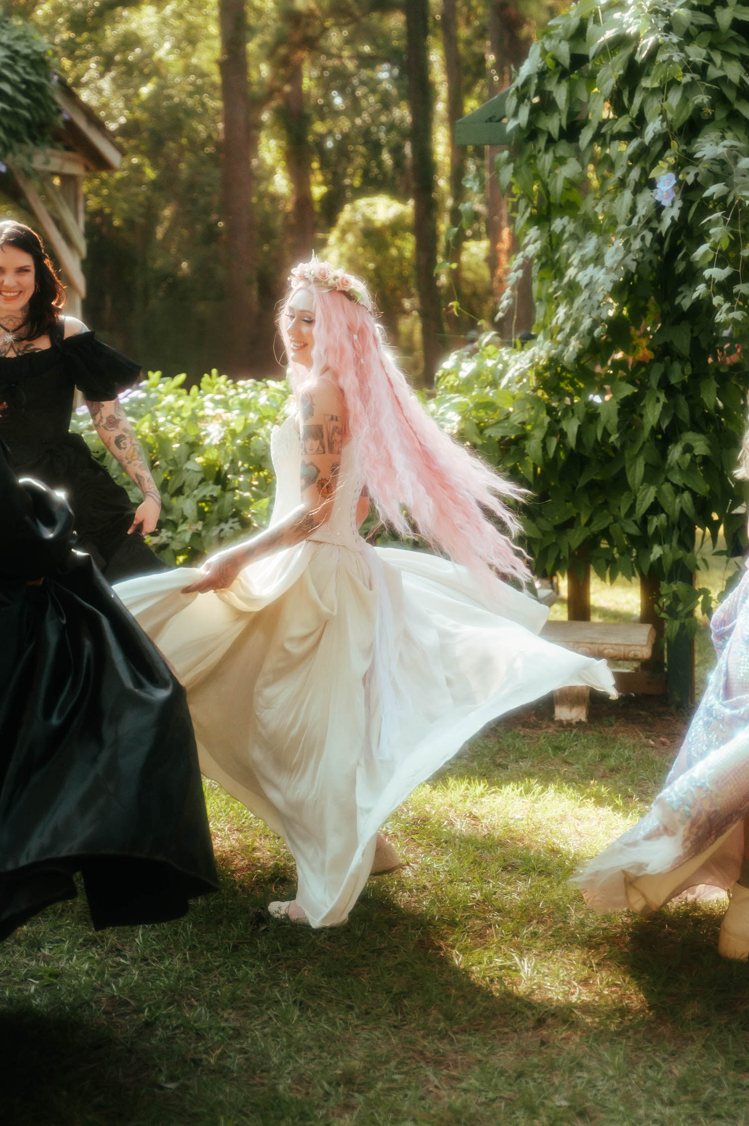 A bride with long pink hair twirls her ivory wedding gown in a sunlit garden during this Texas Renaissance Festival wedding. Royal Lune Photo.