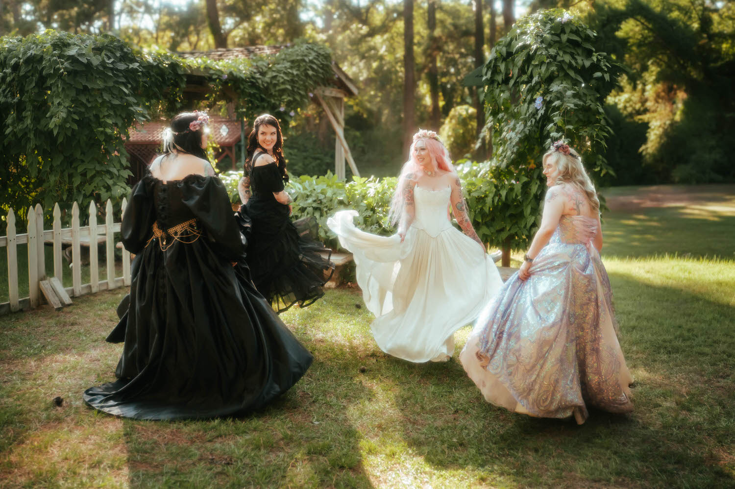 The wedding party spins together in front of a vine covered pergola, capturing the joyful energy of this Renaissance festival wedding. Royal Lune Photo.