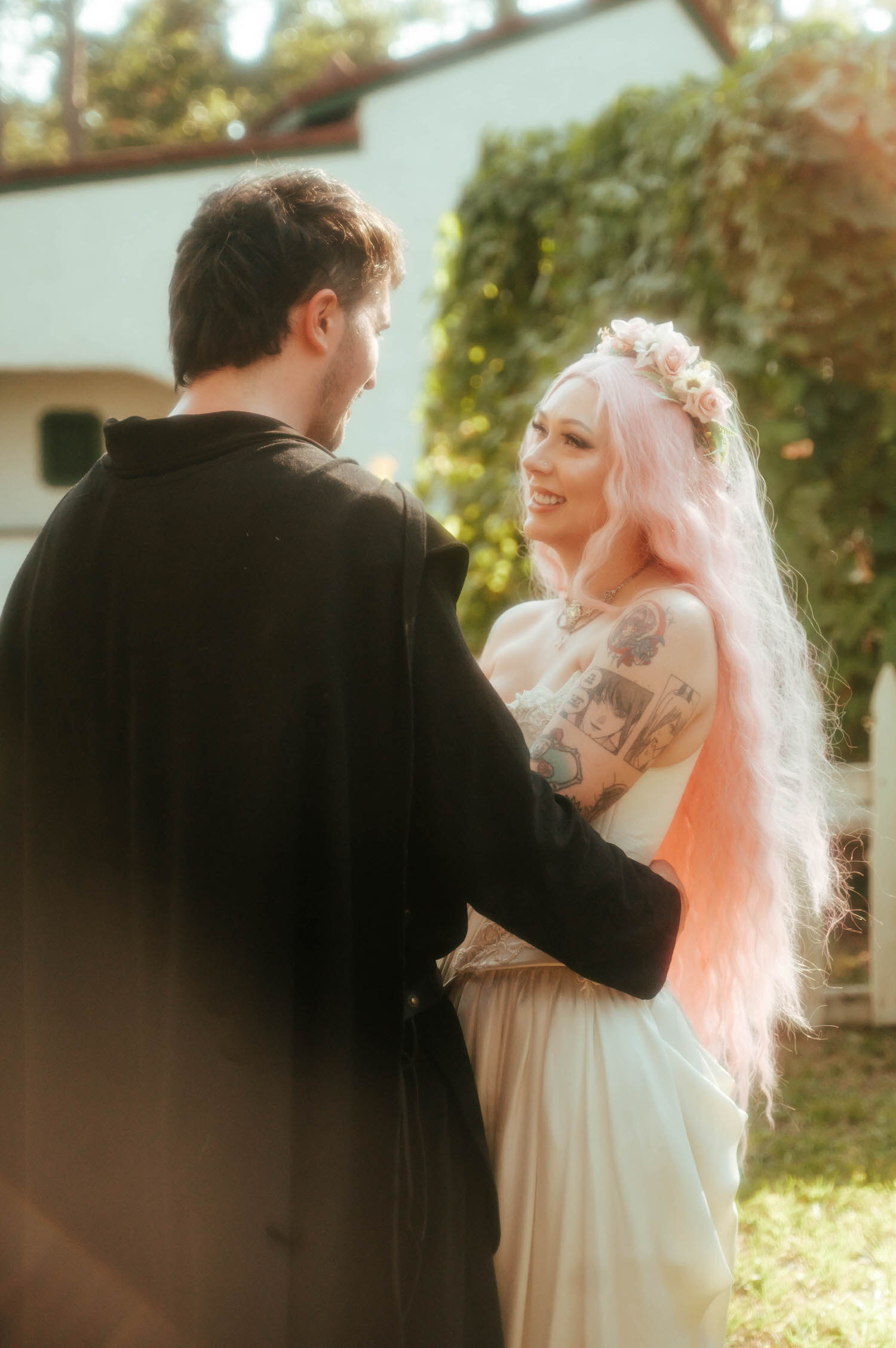 The bride reaches up to touch the groom's face as they dance together near a white picket fence, her pink hair cascading down her back. Sweet, swaying moments like this are a highlight of any Texas Renaissance Festival wedding photographer's coverage. Royal Lune Photo.