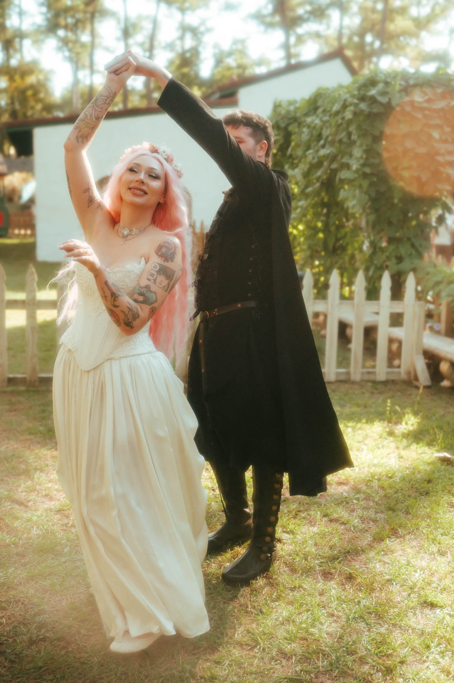 The bride twirls under the groom's raised arm as they dance together on the lawn, her gown flowing around her. Playful dance moments like this bring energy to a Texas Renaissance Festival wedding photographer's gallery. Royal Lune Photo.