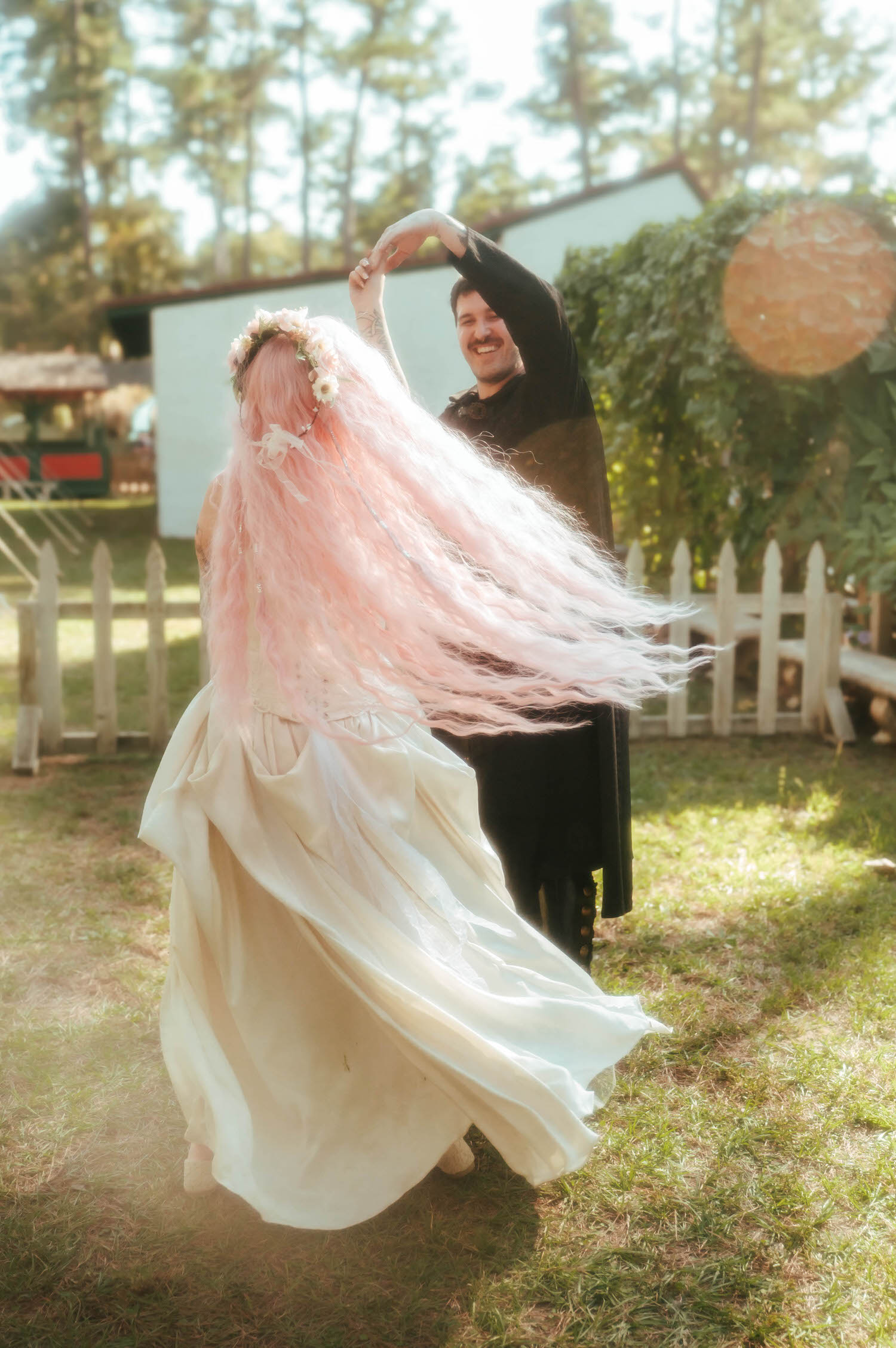 The bride spins with her pink hair fanning out dramatically as the groom laughs and guides her through the dance. Dynamic, joyful shots like this capture the fun of a Renaissance festival wedding. Royal Lune Photo.