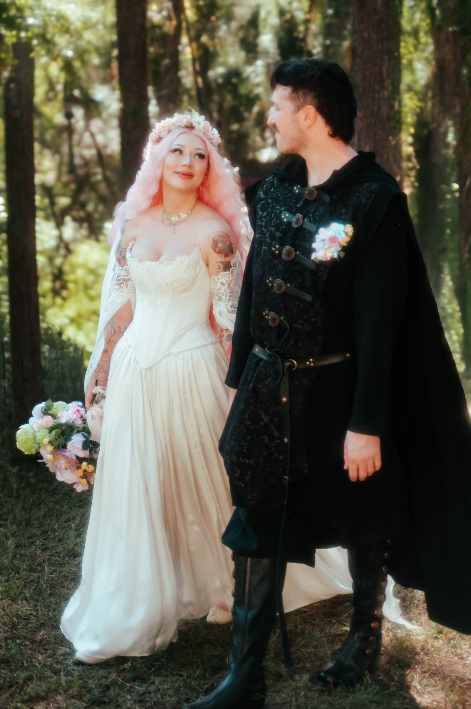 The bride and groom walk together through the wooded festival grounds, her Firefly Path Bridal Gown and bouquet trailing as they head toward the Italian Village reception. This transitional moment reflects the unique flow of a Texas Renaissance Festival wedding. Royal Lune Photo.