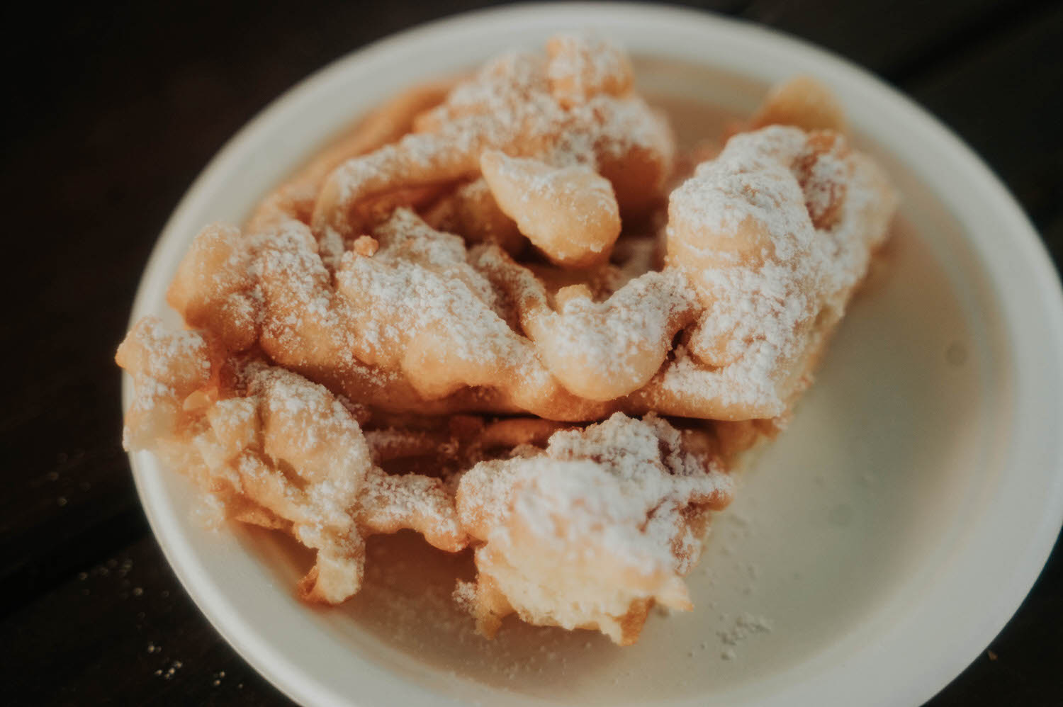 A plate of powdered sugar dusted funnel cake sits on the reception table, a classic festival treat served to guests. Sweet details like this add to the charm of a Texas Renaissance Festival wedding. Royal Lune Photo.