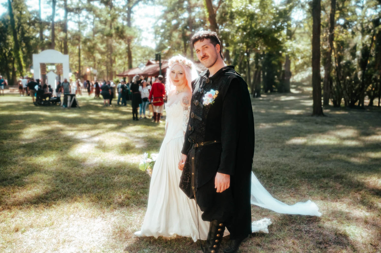 The bride and groom pose together in the dappled forest light near the festival pathway, her bouquet and his floral boutonniere adding soft color to his all black attire. Portraits like this bridge the ceremony and Italian Village reception beautifully. Royal Lune Photo.