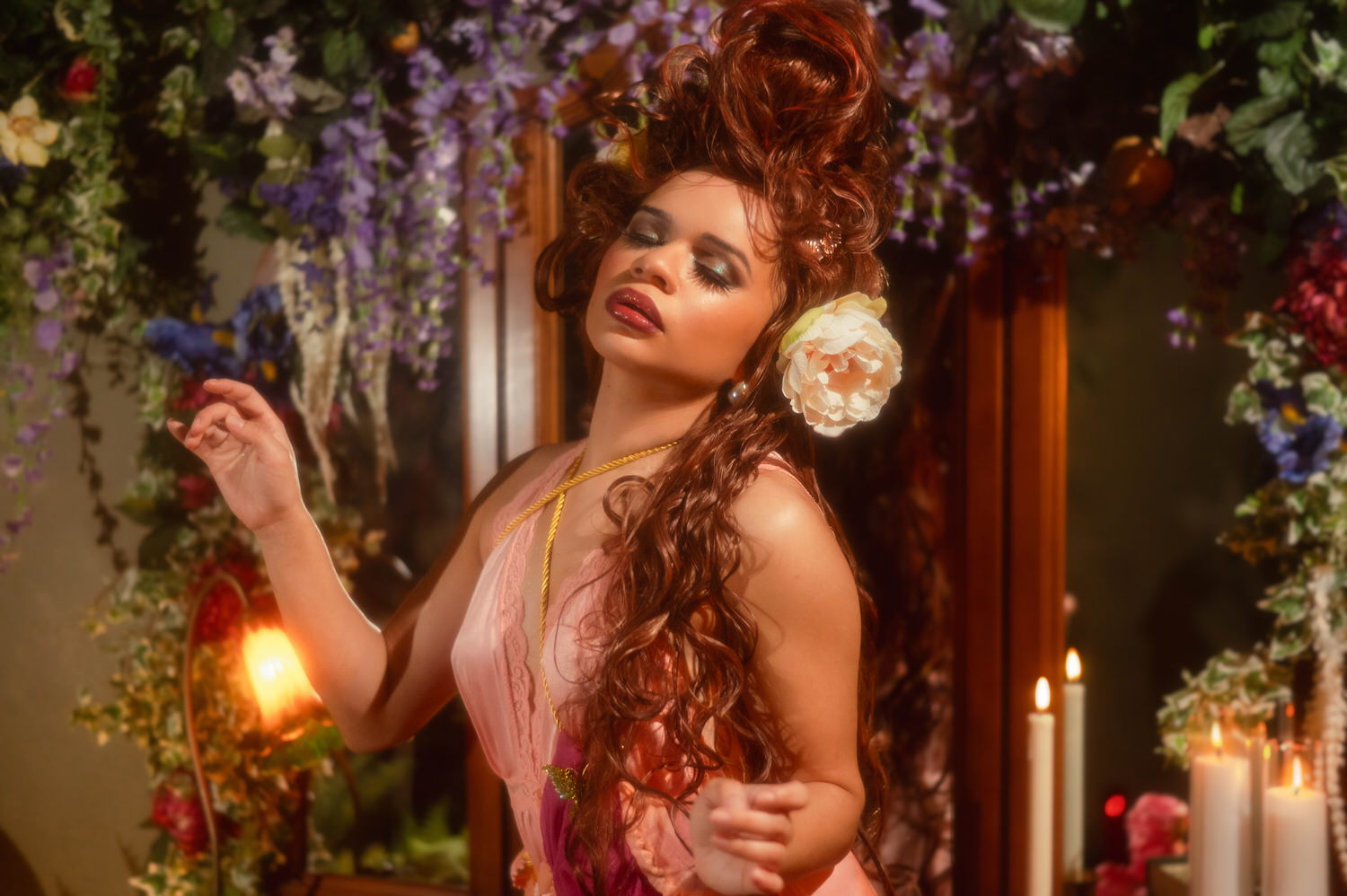 Woman with a cream peony tucked into her wig turning gently to the side in front of lit taper candles, Royal Lune Photo.