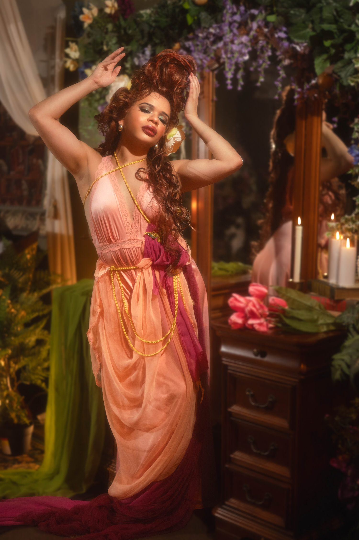Woman with hands raised to her curling upswept wig in this mucha inspired photoshoot set against a wall of purple wisteria, Royal Lune Photo.
