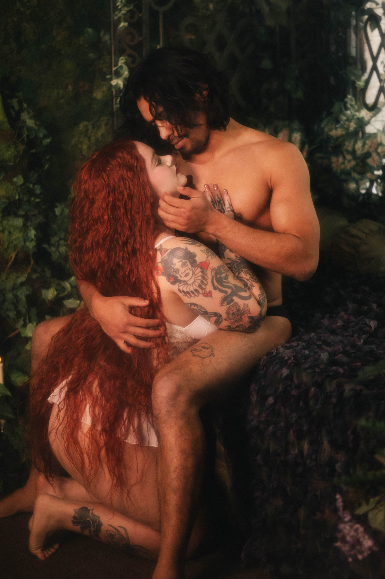 A statue inspired photoshoot pose shows the couple wrapped in a close embrace, the woman's face resting against her partner's chest as his tattooed arm cradles her. Royal Lune Photo