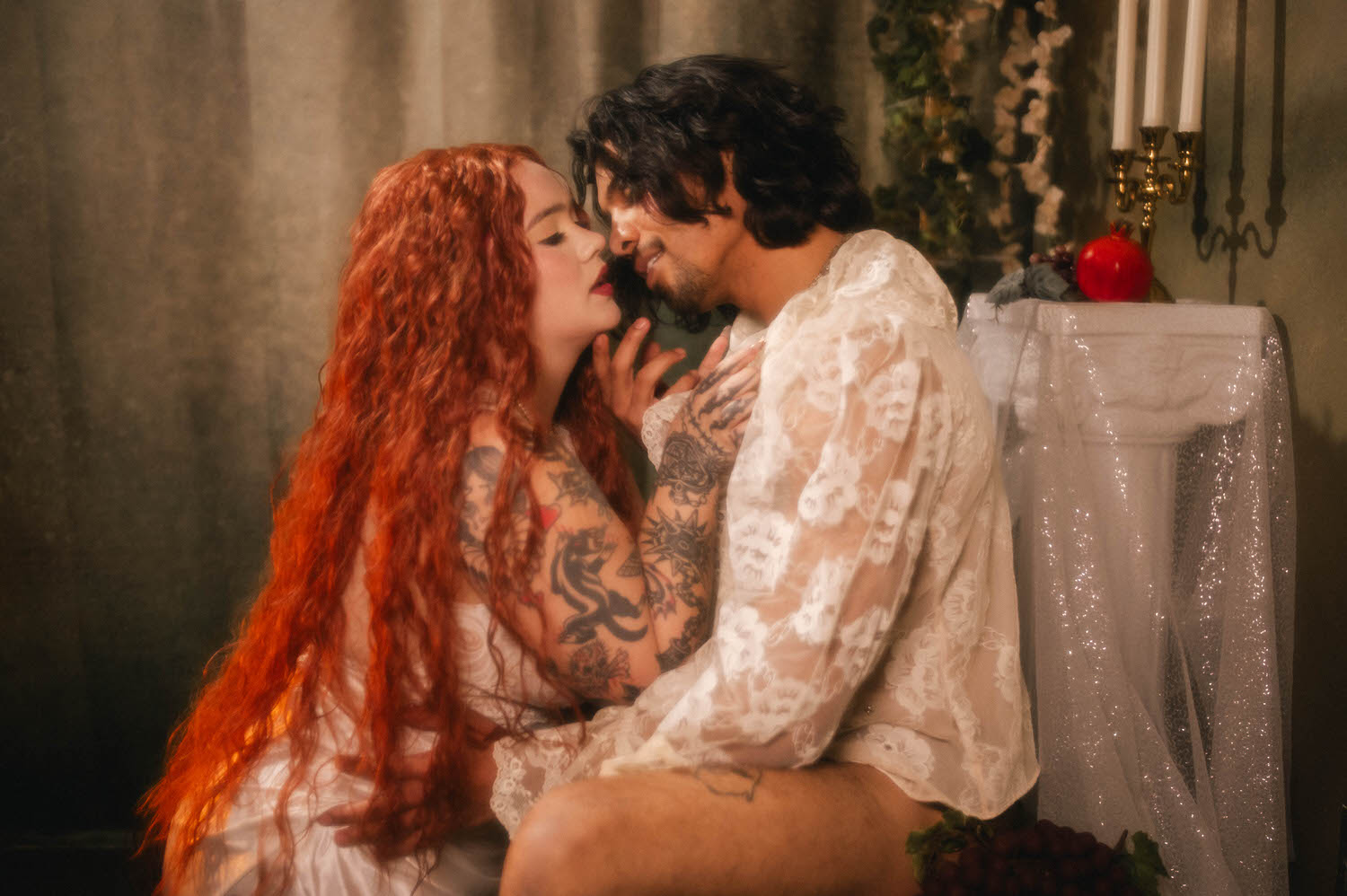 A statue inspired photoshoot pose shows the couple nearly touching foreheads beside a gold candelabra, sheer lace catching the candlelight between them. Royal Lune Photo