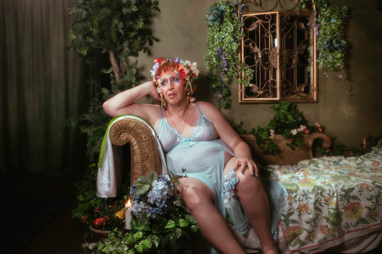 This self expression through art image shows a woman resting her head against her hand on a carved wooden bench arm, a pale blue floral garter at her knee, with blue hydrangea blooms and a lit candle nearby. Royal Lune Photo