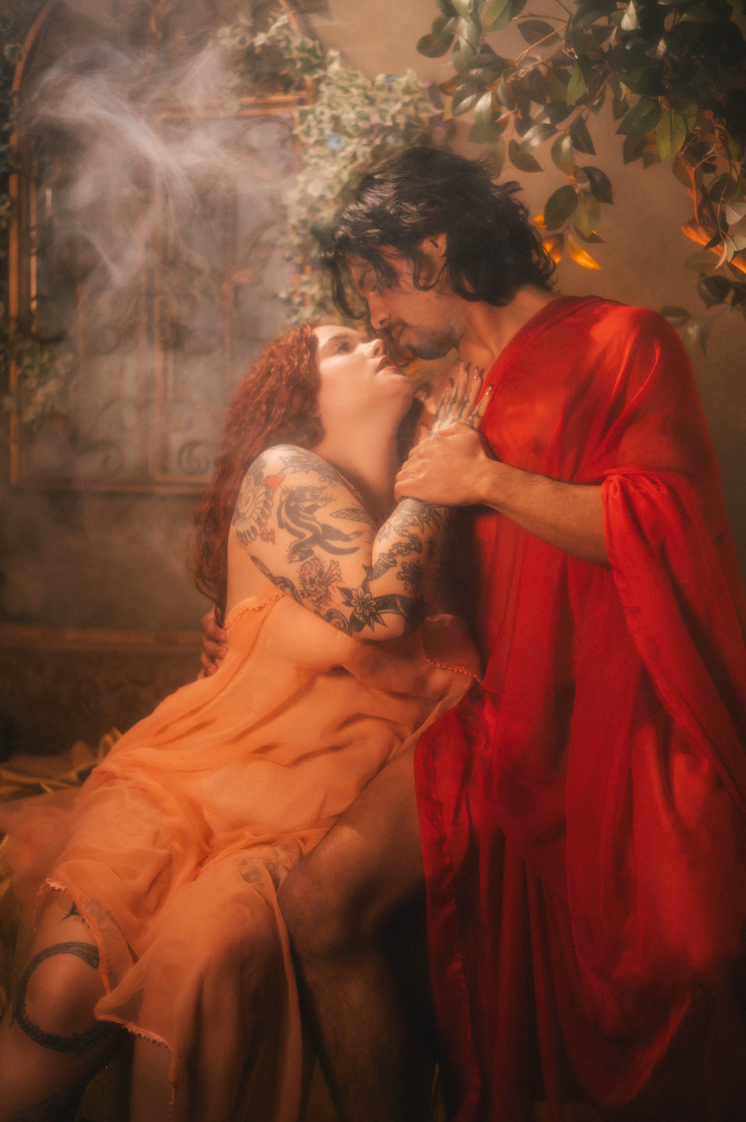 A couples boudoir photoshoot idea styled after classical sculpture, the pair locked in an embrace as trailing smoke drifts through candlelight around them. Royal Lune Photo