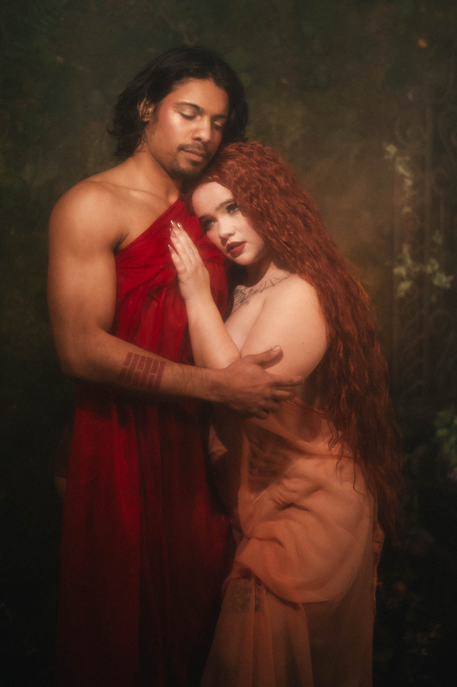 Dallas Fort Worth boudoir photographer captures a quiet embrace between the couple, the woman resting her head against her partner's chest in wet red silk. Royal Lune Photo
