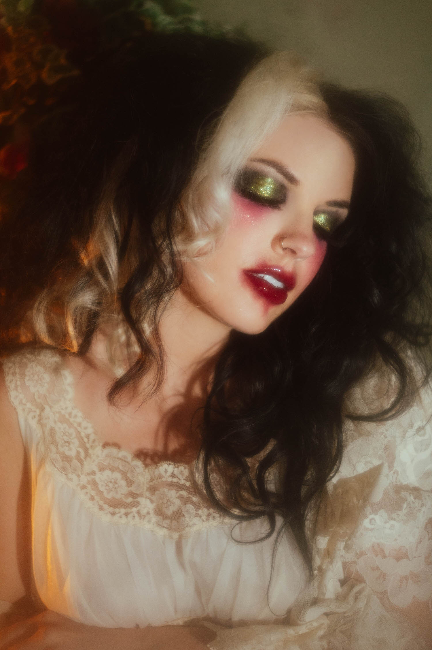 A close up portrait shows a model with shimmering green eyeshadow and deep red lips in soft candlelight in this moody poetry photoshoot by Royal Lune Photo.