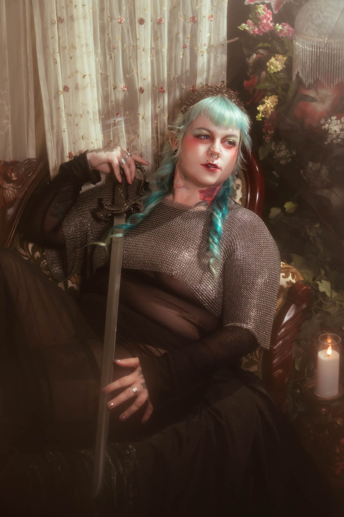 A content photography for creatives in Dallas image of a woman reclining on a vintage tufted sofa with a glowing bladed sword laid across her chainmail top, eyes closed beside a lit candle, Royal Lune Photo.