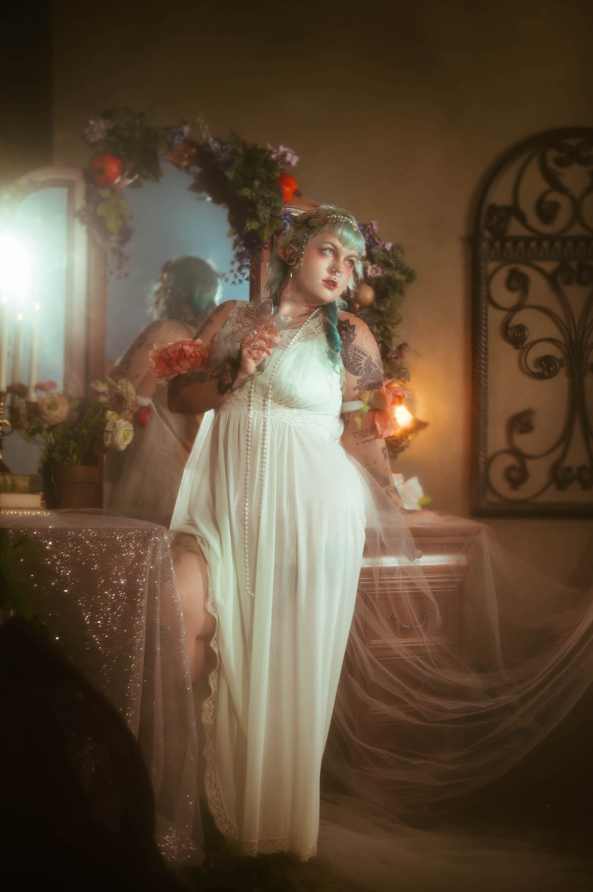 A content photography for creatives in Dallas portrait of a woman in a pale mint nightgown holding a small pink flower charm and pearls, standing beside an antique mirror decorated with fruit and greenery, Royal Lune Photo.