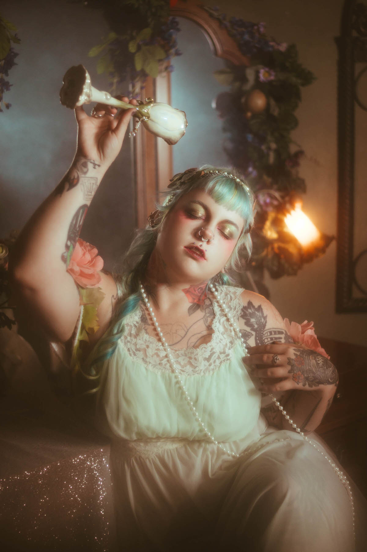 A tattoo artist branding photoshoot image of a woman with her tattooed arm raised holding an ornate white chalice above her head, eyes closed with a pink rose tucked at her shoulder, Royal Lune Photo.