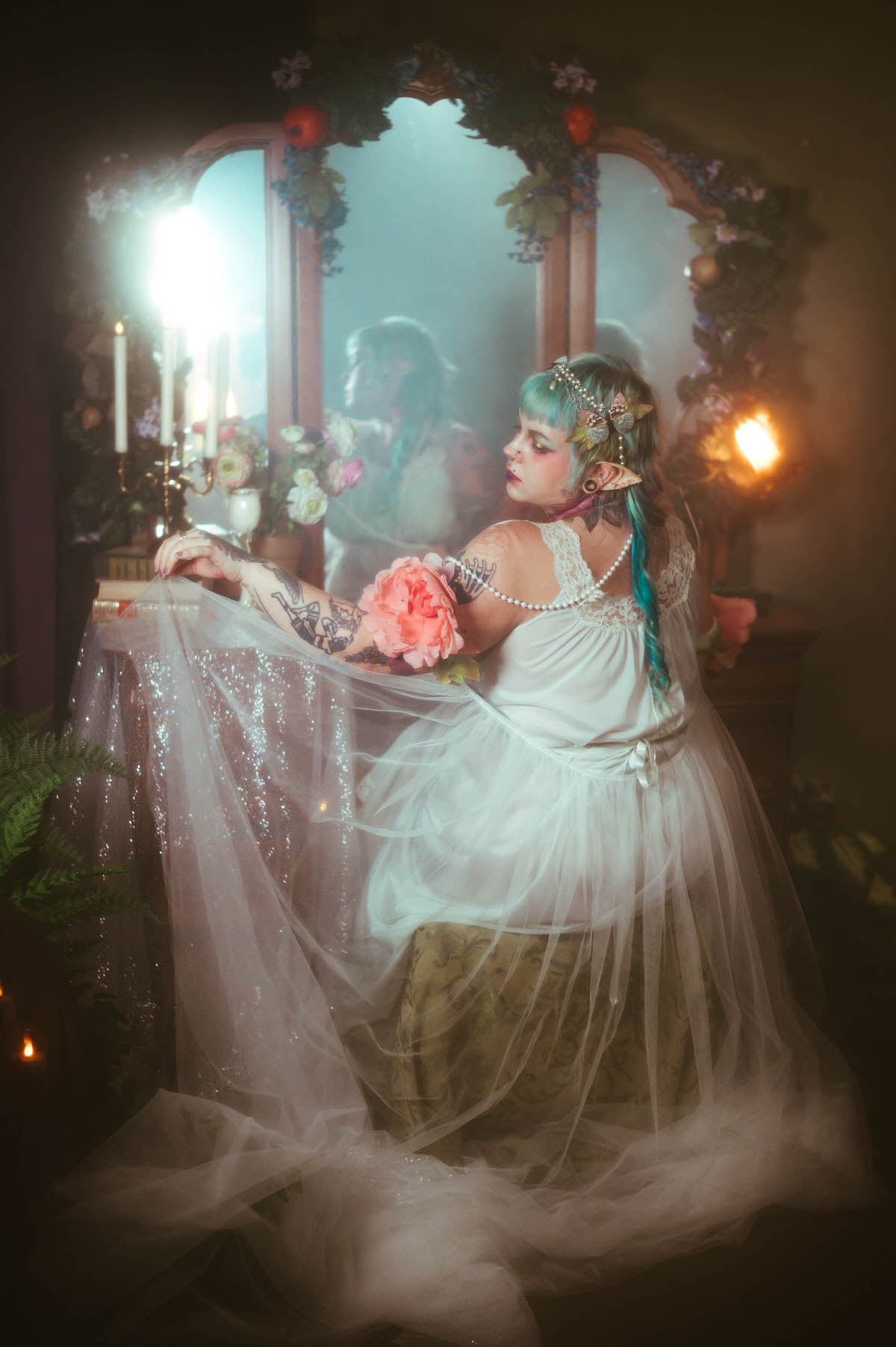 A Dallas Fort Worth branding photographer image of a woman seen from behind at a vanity mirror, holding sheer sparkling tulle fabric that pools across the table beside a lit candelabra, Royal Lune Photo.