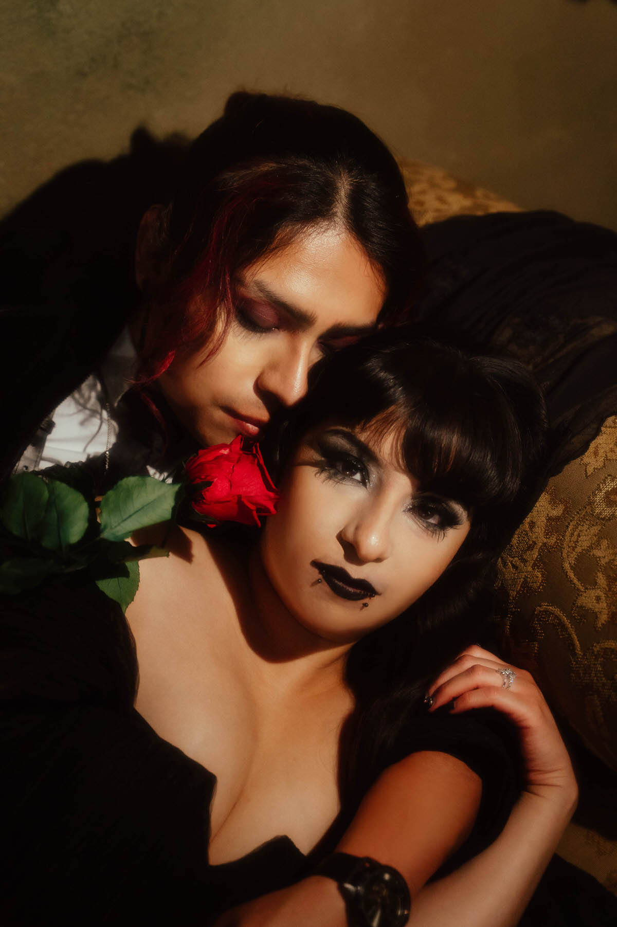 Close-up of a couple nuzzling with a red rose between them for dark fantasy engagement photos