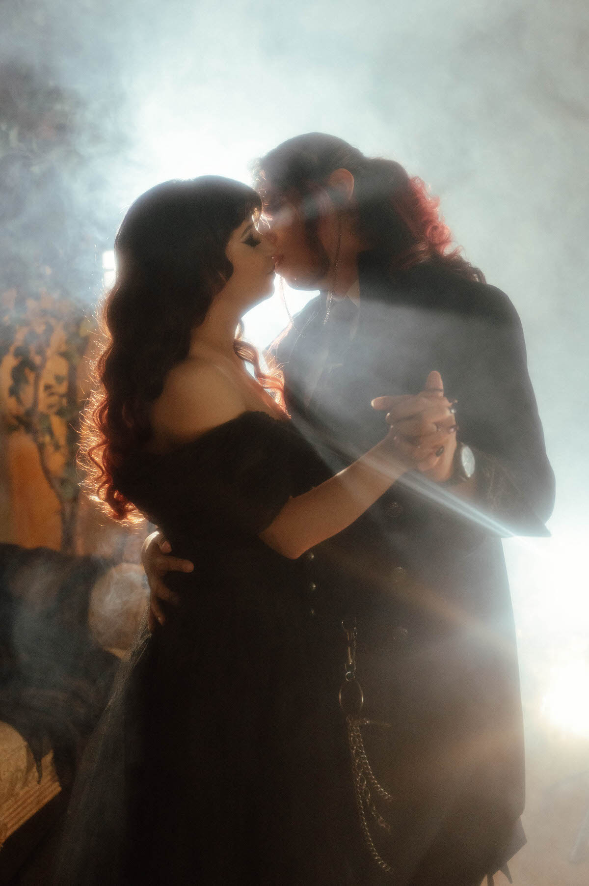 Couple kissing while dancing in backlit fog and lens flare, taken by an alternative engagement photographer in Dallas