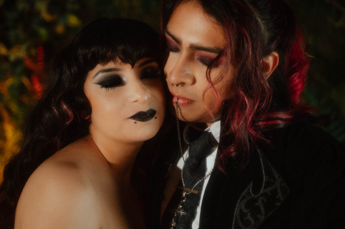Close-up of a couple cheek to cheek with dramatic eye makeup and black lipstick for dark romantic engagement photography